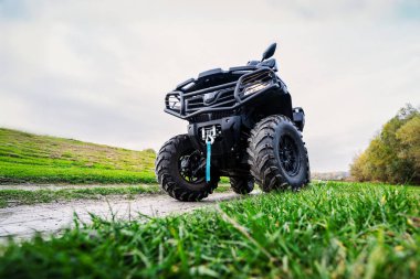 Düşük açılı bir fotoğraf, çimenli bir yolda engebeli lastikleri olan, doğa ortamlarında macerayı ve dayanıklılığı vurgulayan bir arazi aracını gösteriyor..