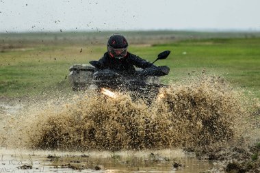 Korkusuz bir motosikletçi, maceralı bir off-road gezisi sırasında çamurlu sularda süzülür. Doğal bir manzara ortamında adrenalin ve heyecan sergiler..