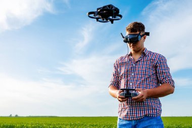 FPV gözlük takan çiftçi buğday tarlasında tarım insansız hava aracı kullanıyor.