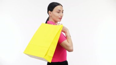 Genç, güzel bir kadın. Elinde torbalarla arka planda.