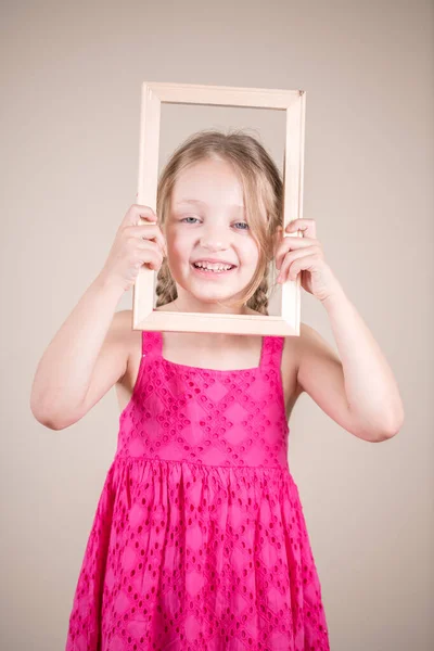 穿着粉色衣服和木制框架的小女孩 — 图库照片
