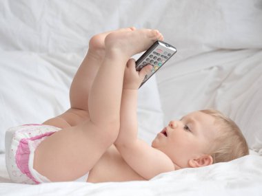 Bebek uzanıyor ve uzaktan kumandayla oynuyor