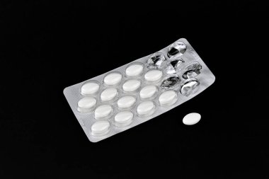 A pack of pills with a white pill in the middle. The pills are in a silver wrapper