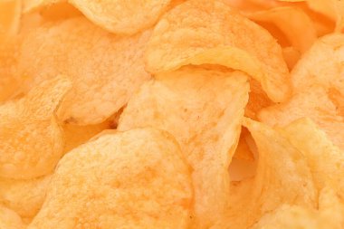 Patates cipsi yığınına yakın çekim. Çipler altın gibi ve çıtır çıtır ve her yere saçılmış. Sahne hoşgörü ve baştan çıkarıcılıktır.