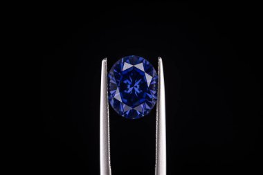 Mavi bir elmas beyaz metal bir nesnenin üzerinde. Elmas kesilmiş ve cilalanmış, ve sergileniyor.