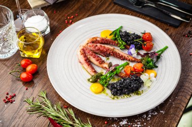 Siyah pilavlı ahtapot. Havuç kreması, mini brokoli, fesleğen sosu. Modern gurme yemek restoranında öğle yemeği olarak sunulan lezzetli, sağlıklı geleneksel yemekler..