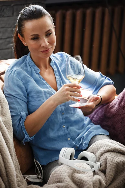 余暇の概念 幸せな美しい女性はソファの上に座ってガラスから白ワインを飲む屋内 女性過ごす彼女の自由日とリラックスで自宅一人で — ストック写真