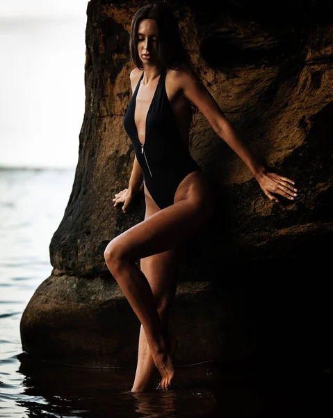夏のレクリエーションの概念 ビーチで水の中に黒の水着ビキニを着てフィット訓練されたスリムボディを持つ美しい若いセクシーな女性が立っています 海におけるファッション女性モデルのポーズ — ストック写真