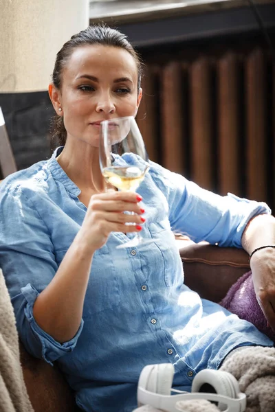 余暇の概念 幸せな美しい女性はソファの上に座ってガラスから白ワインを飲む屋内 女性過ごす彼女の自由日とリラックスで自宅一人で — ストック写真