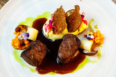Geyik filetosu. Yer mantarlı patates püresi, porcini mantarı fırında pırasa ve havuç, ardıç ekmeği, porto şarabı sosu. Modern gurme restoranında öğle yemeği olarak sunulan lezzetli, sağlıklı geleneksel yemekler..