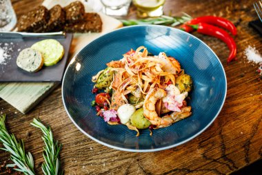 Arjantin kral karidesli sıcak salata. Badem patatesi, mini romaine marulu, havuç, vişneli domates, pesto, siyah kök cipsi, karamelli ceviz, pancar balzamisi. Modern restoranda yemek servisi..