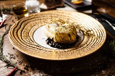 24 karat altın kaplanmış siyah Angus fileto bifteği, patates püresi, böğürtlenli kırmızı şarap sosu, bir tabakta rosmarine. Modern gurme mutfağında öğle yemeği için lezzetli ve sağlıklı yemekler servis ediliyor..