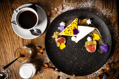 Tutkulu meyveli cheesecake, incir ve portakal tabakta. Modern gurme mutfağındaki bir masada öğle yemeği olarak sunulan lezzetli ve sağlıklı yiyecekler..