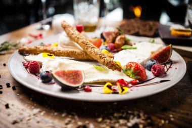 İki kişilik peynir tabağı: keçi peyniri kreması, gorgonzola, camembert, grissini ve incir reçeli. Lezzetli sağlıklı İtalyan geleneksel yemekleri modern gurme mutfağında öğle yemeği için servis edilir..