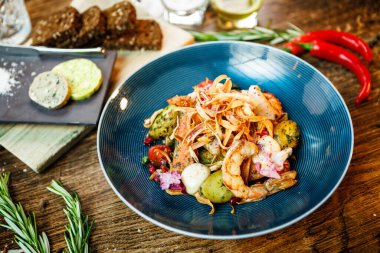 Arjantin kral karidesli sıcak salata. Badem patatesi, mini romaine marulu, havuç, vişneli domates, pesto, siyah kök cipsi, karamelli ceviz, pancar balzamisi. Modern restoranda yemek servisi..