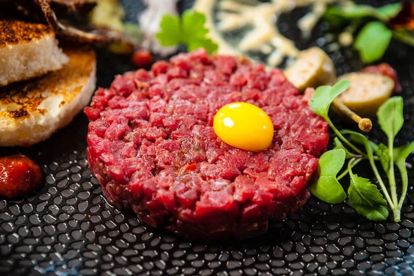 stock image Beef tartare from Black Angus. Onion, quail egg, tomato sauce, mustard mayonnaise. Delicious healthy Italian traditional food closeup served for lunch in modern gourmet cuisine restaurant.