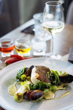 Karnabahar kremalı morina filetosu, kuşkonmaz, istiridye şarabı sosu ve misket tüfeği. Lezzetli deniz ürünleri yakın çekim modern mutfak gurme restoranında öğle yemeğinde servis edilir..