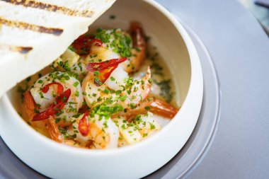 Karides pil pil. Kral karides, sarımsak, biber ve baget. Lezzetli İspanyol geleneksel yemekleri modern gurme mutfağında öğle yemeği için servis edilir..