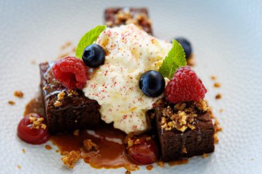 Tuzlu karamelli kek. Anglaise köpüğü, ahududu sosu, ceviz ve taze böğürtlen. Modern gurme yemek restoranında öğle yemeği olarak sunulan lezzetli tatlı tatlı yemekleri..