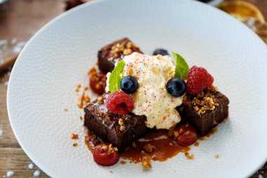 Tuzlu karamelli kek. Anglaise köpüğü, ahududu sosu, ceviz ve taze böğürtlen. Modern gurme yemek restoranında öğle yemeği olarak sunulan lezzetli tatlı tatlı yemekleri..