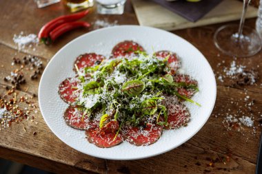 Biftek carpaccio. Borettan soğan, güneşte kurutulmuş domates, mantar sosu roka salatası, parmesan peyniri. İtalyan geleneksel antipasti atıştırmalıkları modern gurme restoranında şarapla birlikte öğle yemeği olarak servis edilir..