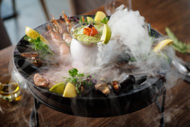 Grilled seafood platter with mussels, shrimp, octopus, and seared tuna. Served with fresh herbs, lemon wedges, and creamy avocado sauce with caviar. Exquisite gourmet dish in a fine dining restaurant. clipart