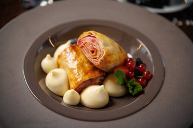 Vanilya kremalı meyveli hamur işi ve yanında da vanilyalı dondurma. Frenk üzümü, yaban mersini ve nane ile süslenmiş. Lüks restoran mutfağında şık bir tatlı..