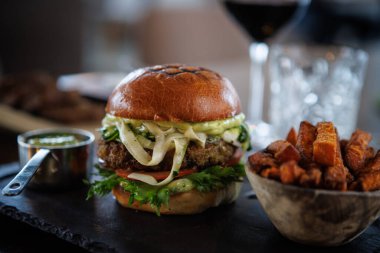 Taze marul, domates, peynir ve soslu sağlıklı vejetaryen burger. Yanında çıtır patates kızartması ve küçük bir bardak sos. Besleyici bir yemek için ideal..