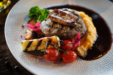 Foie gras ile sulu sığır fileto, kadife ezmeli tatlı patates, ızgara kabak ve vişneli domatesle servis edilir. Sofistike bir yemek ortamında gurme yemeği..
