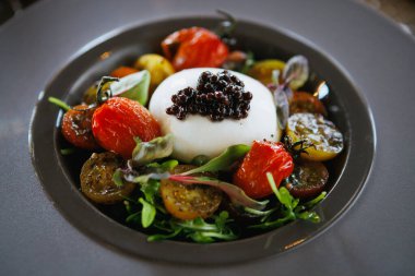 Bu canlı yemek kremalı burrata, kavrulmuş aile yadigarı domatesler ve nefis bir havyar garnitürü içeriyor.