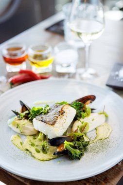 Karnabahar kremalı morina filetosu, kuşkonmaz, istiridye şarabı sosu ve misket tüfeği. Lezzetli deniz ürünleri yakın çekim modern mutfak gurme restoranında öğle yemeğinde servis edilir..