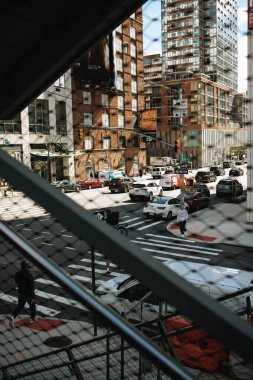 New York City, ABD - 4 Nisan 2024: Arabaları, yayaları ve kentsel binaları olan kalabalık bir Manhattan caddesi. Güneş ışığı, şehir manzarasına gölge düşürür ve günlük yaşamın özünü yakalar..