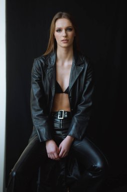 Güçlü sofistike konsept - siyah derili kadın, yoğun bir bakışla oturuyor, onun varlığı sahneyi yönetiyor, karanlık zemin ve cilalı stil yüksek moda havasını artırıyor..