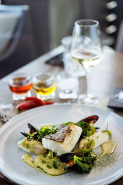 Karnabahar kremalı morina filetosu, kuşkonmaz, istiridye şarabı sosu ve misket tüfeği. Lezzetli deniz ürünleri yakın çekim modern mutfak gurme restoranında öğle yemeğinde servis edilir..