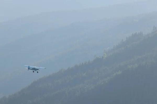 霧の日に山の上を空を飛ぶ飛行機 — ストック写真