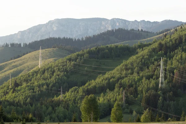 山の風景の緑の牧草地に高電圧電源ライン — ストック写真