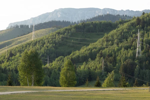 山の風景の緑の牧草地に高電圧電源ライン — ストック写真