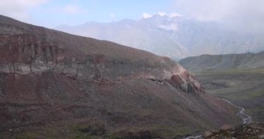 Cacasus dağlarında yalnız başına yürüyüş yapan bir kadın Gergeti buzulu Stepantsminda Gürcistan 'a doğru Kazbek zirvesi yakınlarında.