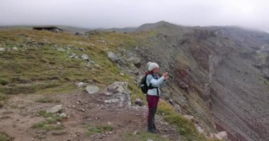 Cacasus dağlarında yalnız başına yürüyüş yapan bir kadın Gergeti buzulu Stepantsminda Gürcistan 'a doğru Kazbek zirvesi yakınlarında.