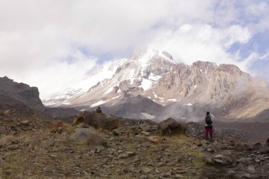 Gürcistan Kafkasya dağlarında yaz boyunca Kazbegi zirvesine doğru dağ yolunda yürüyen bir kadın.