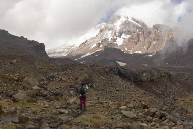 Gürcistan Kafkasya dağlarında yaz boyunca Kazbegi zirvesine doğru dağ yolunda yürüyen bir kadın.