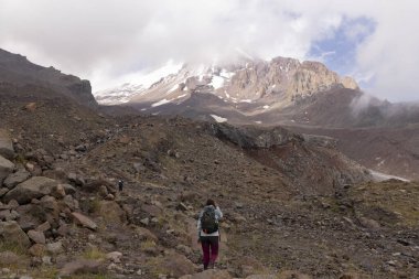 Gürcistan Kafkasya dağlarında yaz boyunca Kazbegi zirvesine doğru dağ yolunda yürüyen bir kadın.