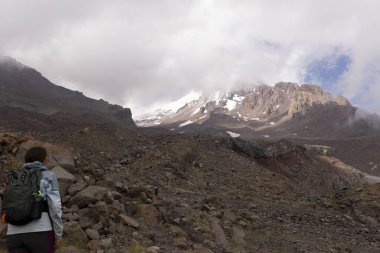 Gürcistan Kafkasya dağlarında yaz boyunca Kazbegi zirvesine doğru dağ yolunda yürüyen bir kadın.