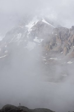 Gürcistan Kafkasya 'daki dağcı silueti sisli yaz gününde Kazbek Dağı' nın sisli manzarasına karşı