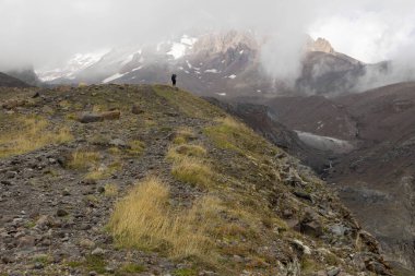 Gürcistan Kafkasya 'daki dağcı silueti sisli yaz gününde Kazbek Dağı' nın sisli manzarasına karşı