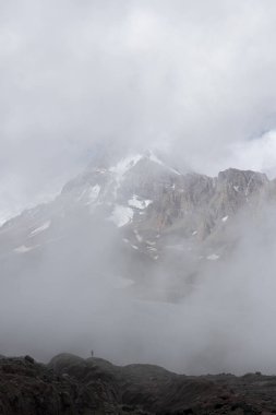 Gürcistan Kafkasya 'daki dağcı silueti sisli yaz gününde Kazbek Dağı' nın sisli manzarasına karşı
