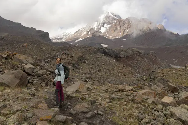 Gürcistan Kafkasya dağlarında yaz boyunca Kazbegi zirvesine doğru dağ yolunda yürüyen bir kadın.