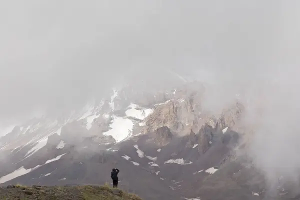 Silhouette of mountain climber in Georgia Caucasus mountains against foggy landscape of mount Kazbek in foggy summer day
