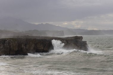 Bufones de Pria, Asturias sahillerinde bulutlu bir günde dalgalı denizlerde ve kıyılarda sprey ile