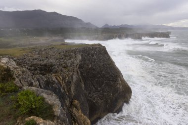 Asturias kıyıları Bufones de Pria 'da bulutlu bir günde dalgalar ve dalgalar kayalık kıyılara vuruyor.